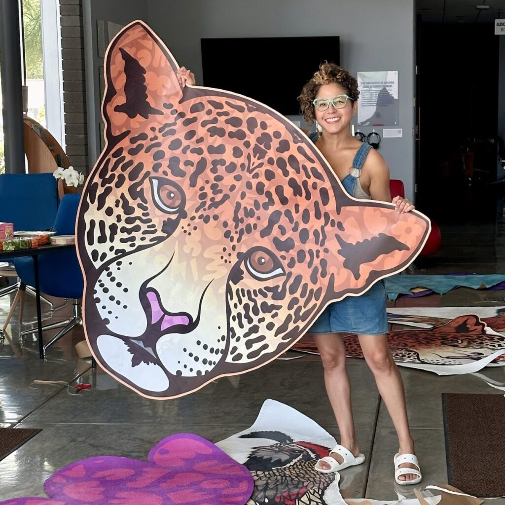 Favianna holds up a large printout of a jaguar in preparation for the installation